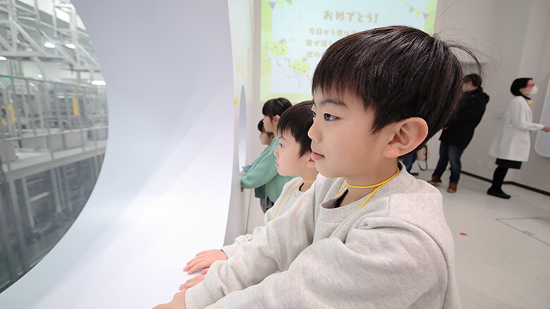 丸く切り抜かれたガラス越しに、実際の製造ラインの現場が見られる