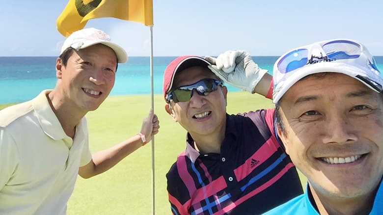 同僚2人とゴルフ場にいる藤江社長の写真